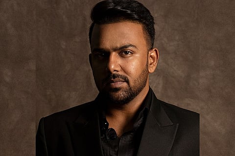 Tharun Bhascker wearing a black shirt and a black blazer