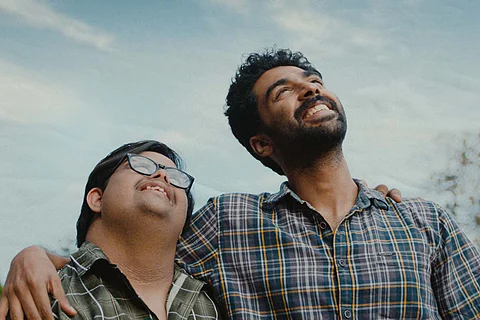 Still from film 'Thirike' two brothers standing together, one's hand over other's shoulder. Both looks up to the sky smiling