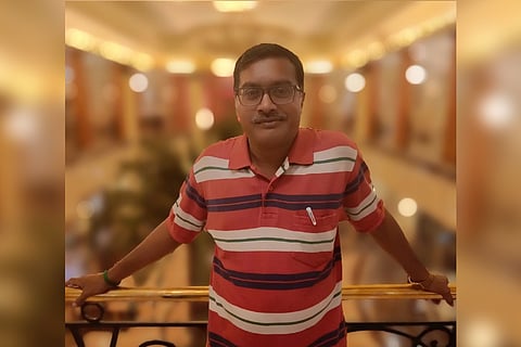 Thirumalai Selvan wearing a red T shirt with white and black horizontal stripes