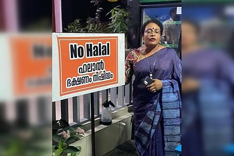 Entrepreneur Tushara Ajith stands near a board that reads, "Non-halal restaurant" in Kerala