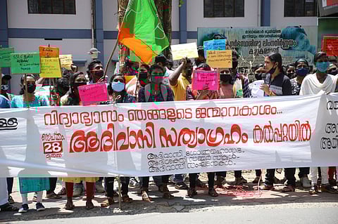 Kerala tribal students protest in street holding a banner for right to higher education