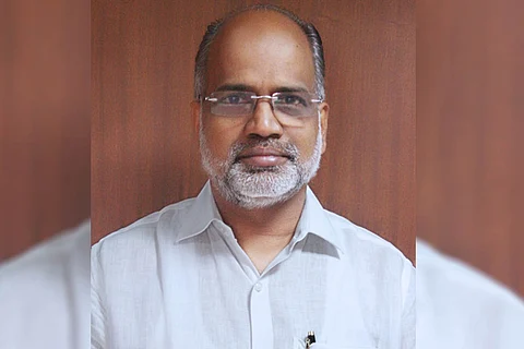 VP Joy IAS, wearing a white shirt and glasses, looking at the camera with a slight smile