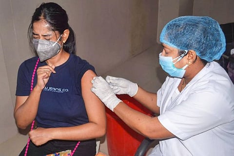 Person wearing a blue shirt receiving COVID-19 vaccine
