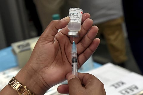 A health worker holding up a syringe and a vaccine bottle in her hands