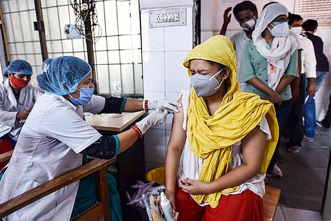 A woman health worker administering COVID-19 vaccine to a woman