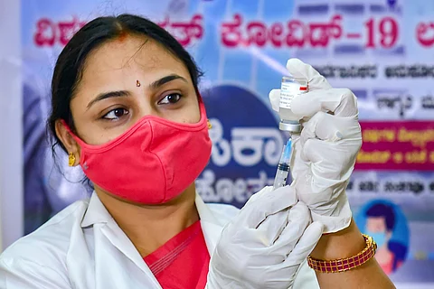 A health worker in Bengaluru uses a syringe to draw from a vial of COVID-19 vaccine