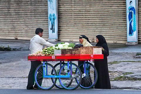 Two women buying from a vegetable cart