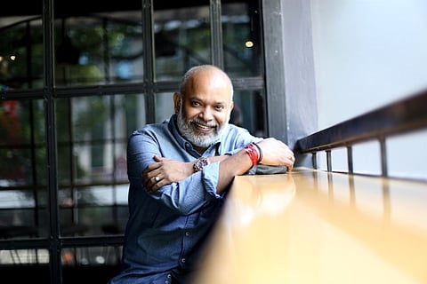 Director venkat Prabhu is seen wearing a blue shirt and is seen looking at the camera in photo.