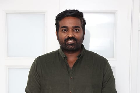 Vijay Sethupathi is seen smiling and striking a pose.