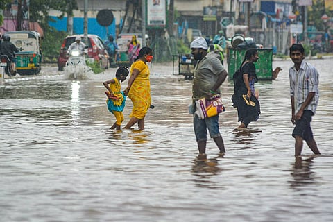 People wade through a waterlogged road during heavy rains in Vijayawada