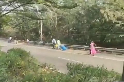 Screenshot from the video where a woman and few others are dragging their suitcases on the road