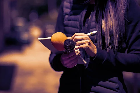 A person holding a mike and notepad, taking notes in it