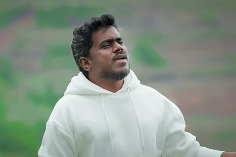Yuvan Shankar Raja is seen singing in the backdrop of trees in the image.