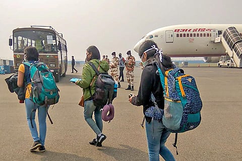 Three women wearing backpacks walking at an airport on their way to board a plane