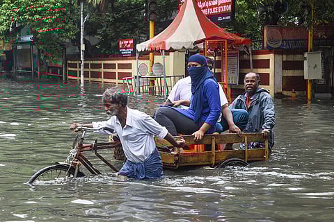 Residents crossing a flooded Chennai street on a rickshaw pulled by an old man