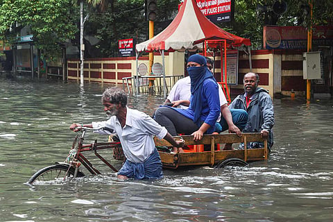 Residents crossing a flooded Chennai street on a rickshaw pulled by an old man