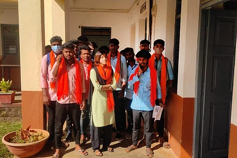 Students in Chikkamagaluru college standing outside a classroom wearing saffron scarves