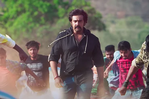 Late actor Chiranjeevi Sarja in a black shirt walking in anger surrounded by men in RajaMarthanda