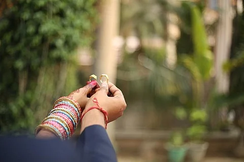One hand each of a couple holding wedding rings
