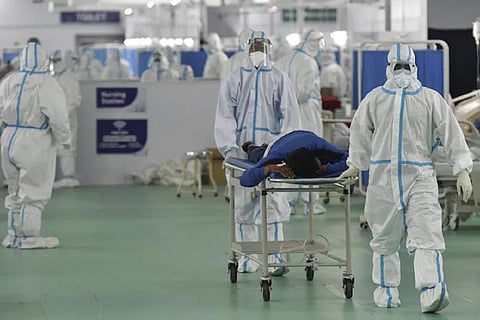 Medical professionals in PPE suits wheeling a patient on a stretcher in a COVID-19 hospital