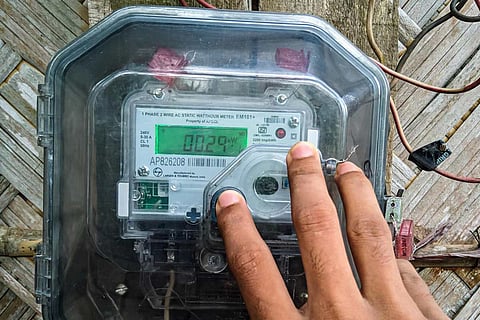 A person's hand on an electric meter