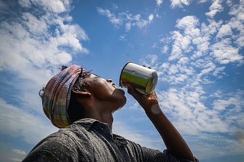A man drinking a glass of water in the heat