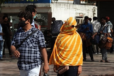 A woman covers her face with a piece of cloth she tries to protect herself from the sun