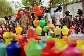 A coloured plastic pots in the image and women waiting to fill water in it.