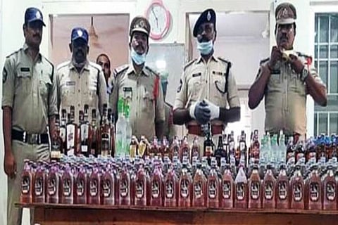 Police officials showcasing the seized liquor in Krishna district