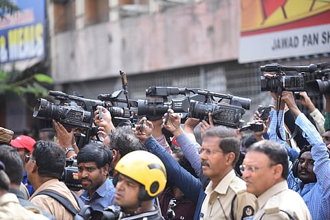 Many camera people can be seen holding cameras and focusing on someone outside the screen, a few cops too in the pictire