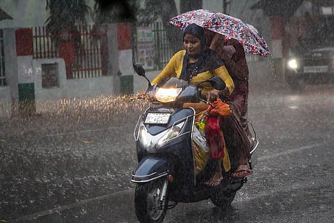 Representative image of a woman riding a scooter in the rain, with another woman sitting behind her