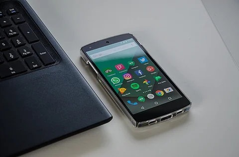 A smartphone with apps like Facebook, instagram, whatsapp next to a laptop
