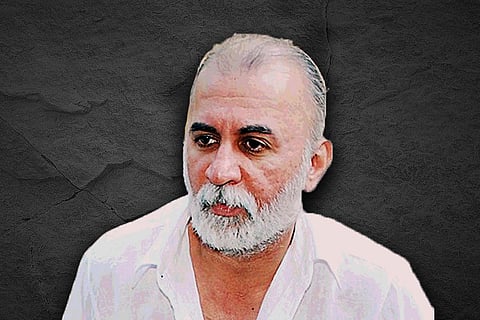 Tarun Tejpal with greying hair and a grey beard wearing a white shirt against a black background