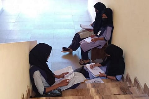 Students wearing hijab and sitting on staircase in protest