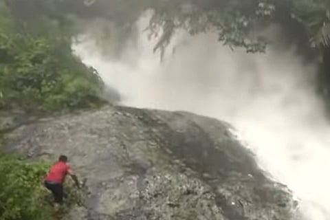 Man climbing rock near waterfalls