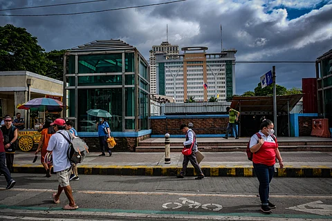 FILE: Commuters pass by the Quezon City Hall on Wednesday, 11 October 2023.
