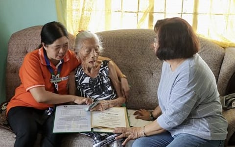 (FILES) CENTENARIAN AWARD. Social workers in Batac City hand over cash incentives to a centenarian on 23 February 2024. The centenarian award of the city government is separate from that of the national government.
