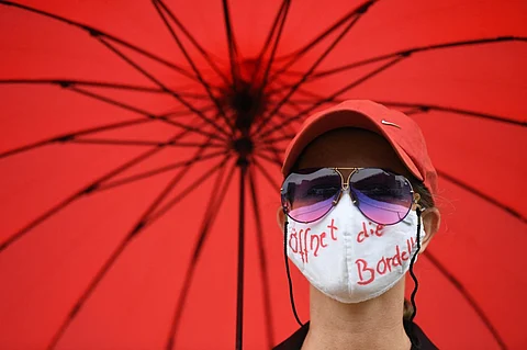 (FILES) A sex worker with a face mask reading 'opens the brothels' stands at a protest to demand the reopening of brothels amid the new coronavirus pandemic at the State Parliament in Duesseldorf, western Germany, on 27 August 2020.