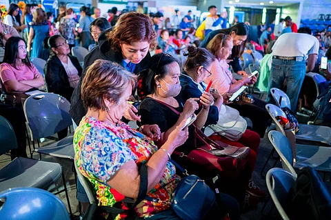 Globe volunteer Janette Patricia Guillen (standing) assists senior participants at Globe’s ‘Teach Me How to Digi’ Learning Session.