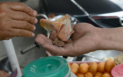 (FILES) A street vendor gives Philippine peso currency change to a customer in Manila.