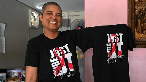 (FILES) In this photo taken on 20 November 2023, Mary Ann Eduarte shows a shirt that she sells for the funding of her cancer treatment at her home in Montalban, Rizal.