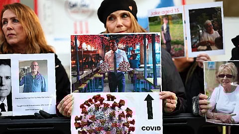 (FILES) Relatives of those who died during the pandemic hold placards as they gathering outside the UK Covid-19 Inquiry building in west London on 11 December 2023.