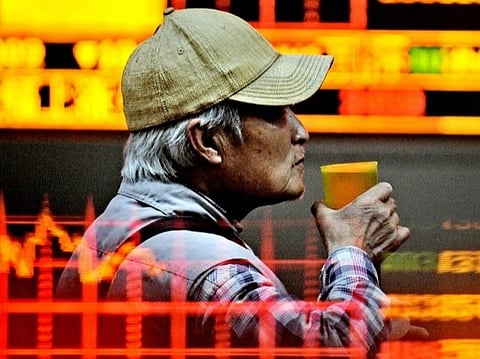 (FILES) A Chinese investor drinks tea as he monitors screens showing stock indexes at a trading house in Shanghai.