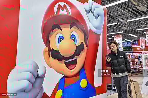 (FILE) This photo taken on 12 January 2024 shows a customer walking past a display for Super Mario by the Japanese gaming company Nintendo, at an electronics store in Tokyo. The Japanese gaming giant is expected to announce third-quarter earnings on 6 February.