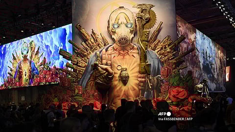 Visitors stand at a poster of "Borderlands 3" at the "Gearbox Software" stand during the Video games trade fair Gamescom in Cologne, western Germany, on 21 August 2019.