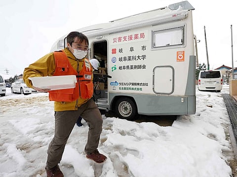 (FILES) This photo taken on 8 January 2024 shows a pharmacist carrying medicine from a mobile pharmacy in the disaster-hit city of Suzu, Ishikawa prefecture, after a major 7.5 magnitude earthquake struck the Noto region in Ishikawa prefecture on New Year's Day. The death toll from a New Year's Day earthquake in Japan climbed to 202 on January 9 with 565 confirmed injured, according to government figures.