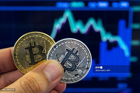 (FILES) A picture taken on 6 February 2018 shows a person holding a visual representation of the digital crypto-currency Bitcoin, at the "Bitcoin Change" shop in the Israeli city of Tel Aviv.