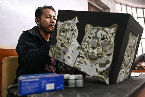 (FILE PHOTO) A Tibetan artisan gives final touches to a 'Thangka', a traditional Tibetan Buddhist painting, in a workshop at the Norbulingka Institute dedicated to preserve Tibetan art and culture in Dharamsala on 20 February 2023. From teaching centuries-old crafts to language lessons, exiled Tibetans guard the cultural identity of a homeland most have neither seen nor dare visit, and where they say Beijing is eradicating their heritage.