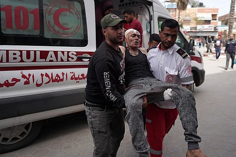 A paramedic and man carry an injured Palestinian from an ambulance to the Al-Aqsa Martyrs hospital in Deir al-Balah following Israeli bombardment in Khan Yunis in the southern Gaza Strip, on March 28, 2024.