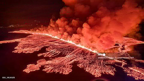 This handout picture released by the Icelandic Coast Guard on 16 March 2024 shows billowing smoke and flowing lava pouring out of a new fissure, during a surveillance flight above a new volcanic eruption on the outskirts of the evacuated town of Grindavik, western Iceland.